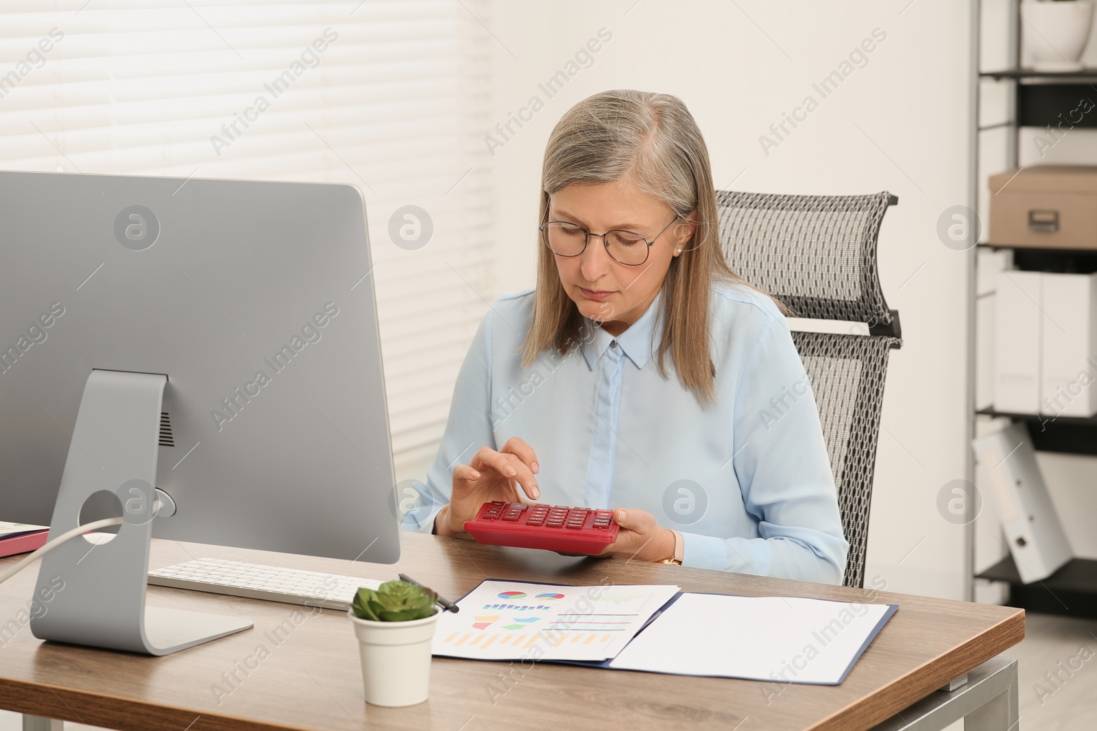 Photo of Senior accountant working at wooden desk in office