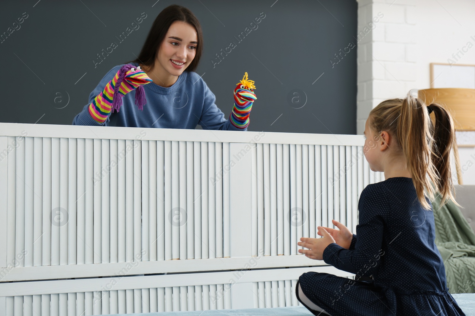 Photo of Mother performing puppet show for her daughter at home