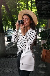 Photo of Beautiful young woman with stylish backpack and camera on city street