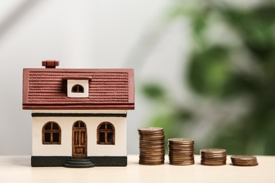 House model and coins on table. Money savings