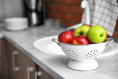 Colander with ripe apples in kitchen