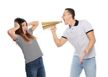 Young man with megaphone shouting at woman on white background