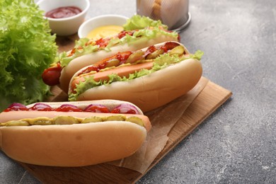 Delicious hot dogs with different toppings served on grey table. Space for text