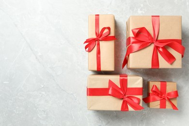 Photo of Christmas gift boxes with red bows on light grey marble background, flat lay. Space for text