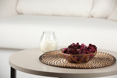 Photo of Aromatic potpourri of dried flowers in bowl and candle on white table indoors. Space for text