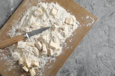 Making shortcrust pastry. Flour, butter, knife and wooden board on grey table, top view