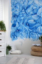 Photo of Stylish living room with blue flowers painted on wall. Floral pattern in interior design