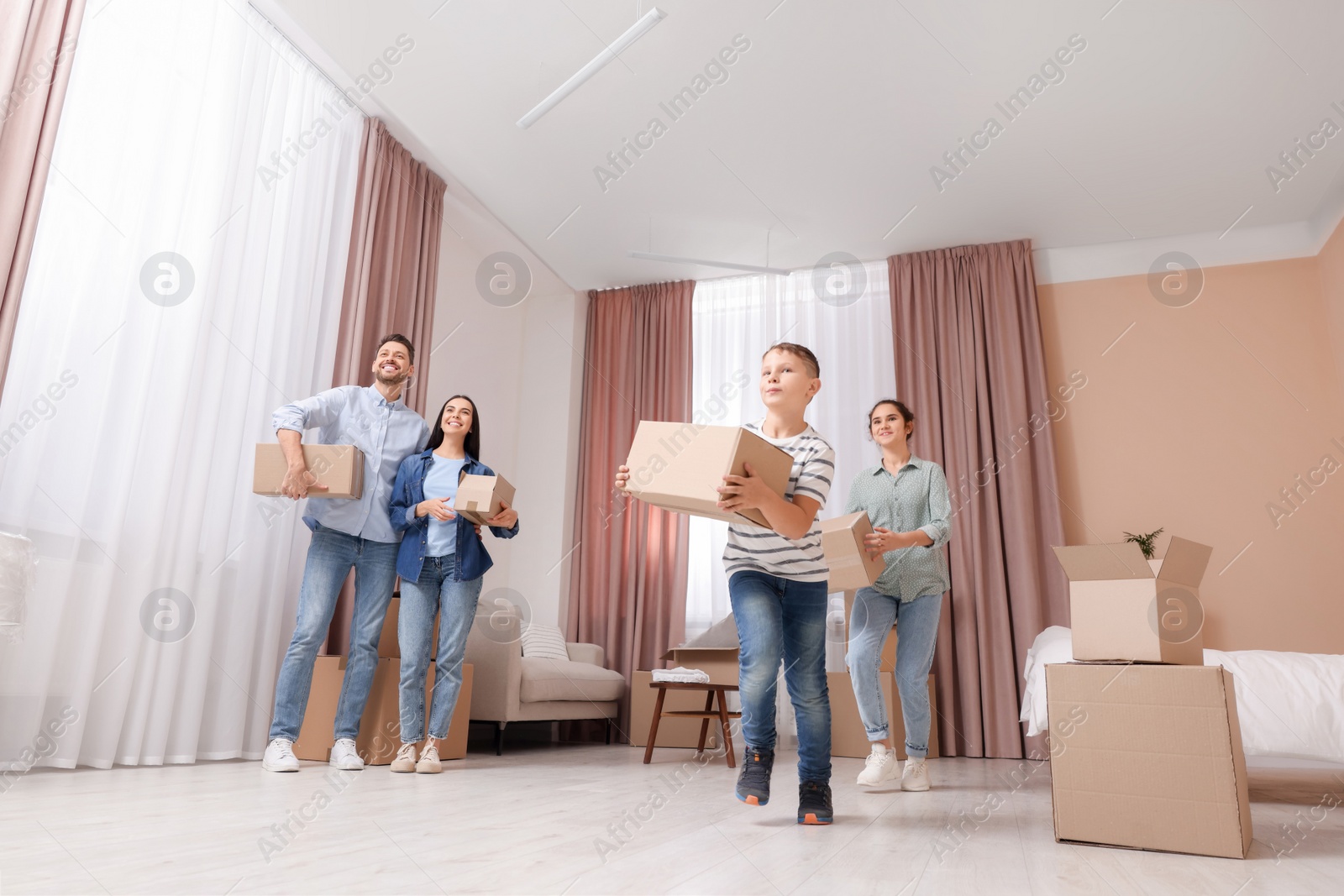 Photo of Happy family with moving boxes in apartment. Settling into new house