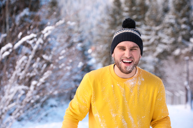 Photo of Happy young man playing snowballs outdoors. Winter vacation