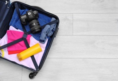 Packed suitcase on wooden background with space for text, top view