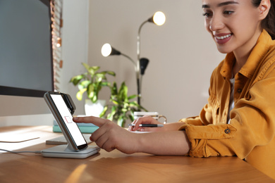 Woman at desk, smartphone and watch on wireless charger. Modern workplace