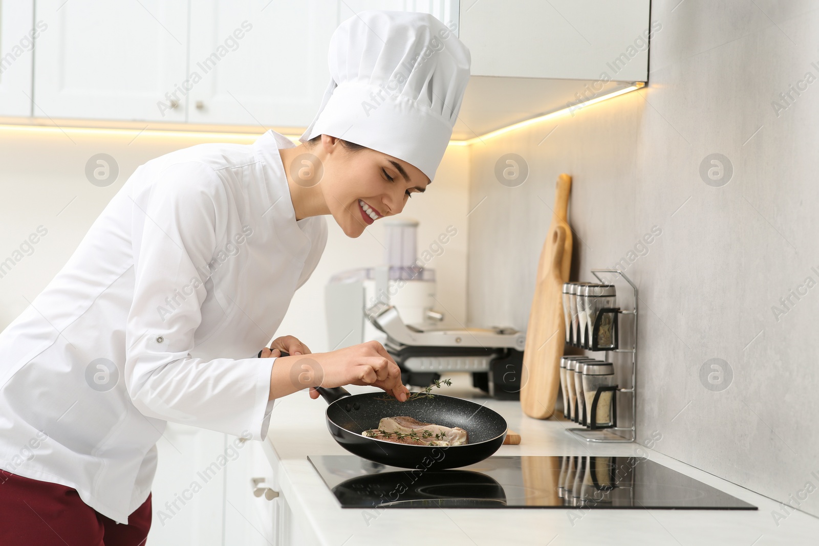 Photo of Professional chef adding thyme into frying pan in kitchen