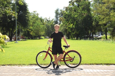 Attractive man with bike outdoors on sunny day