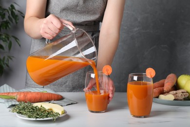 Woman pouring carrot juice from jug into glass, closeup