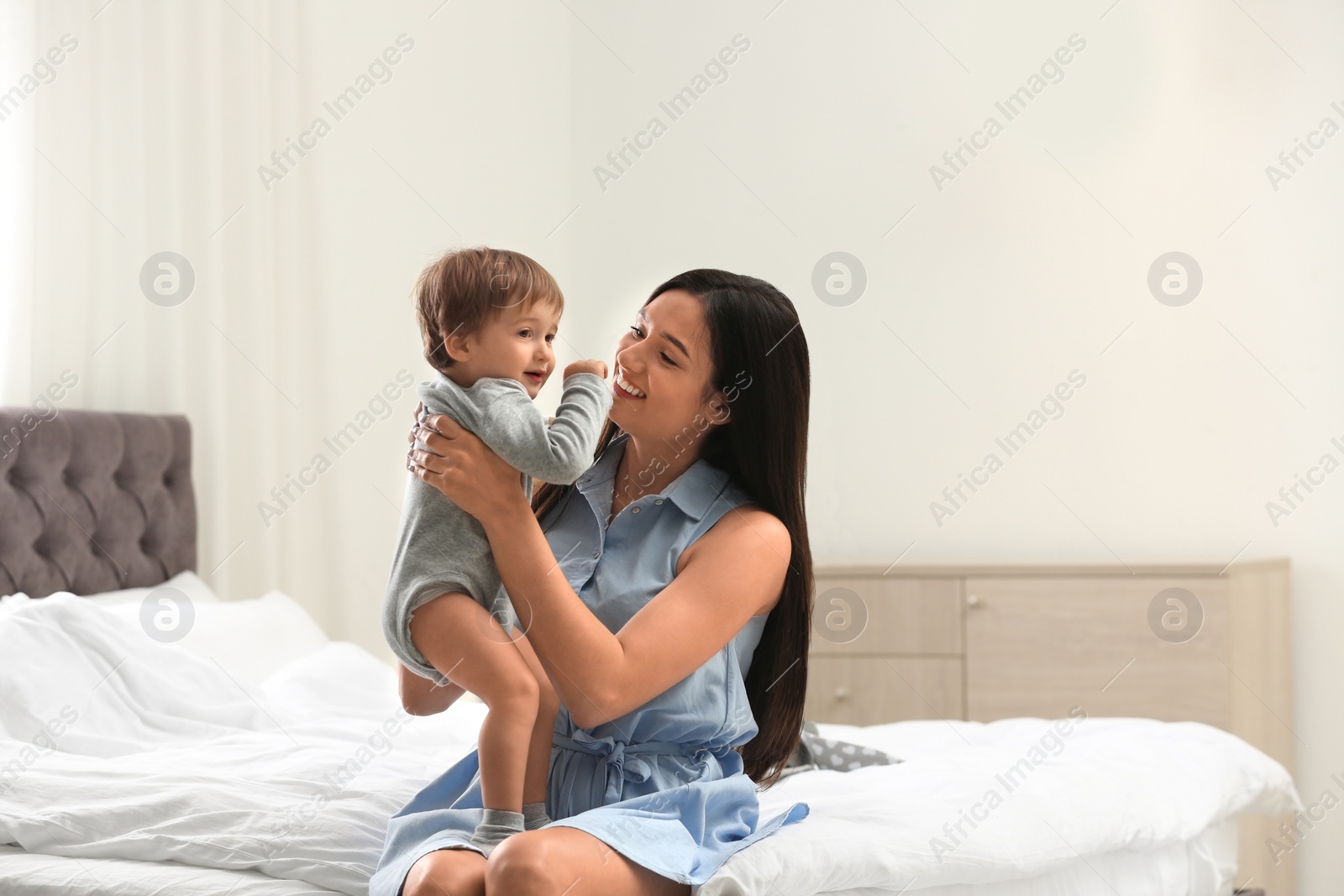 Photo of Young nanny with cute little baby in bedroom