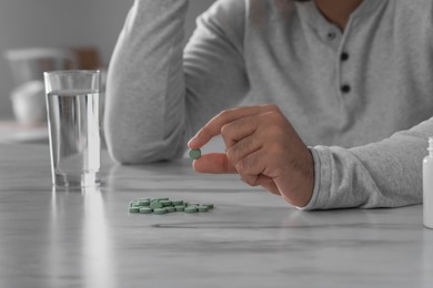 Photo of Man holding antidepressant pill at white marble table indoors, closeup