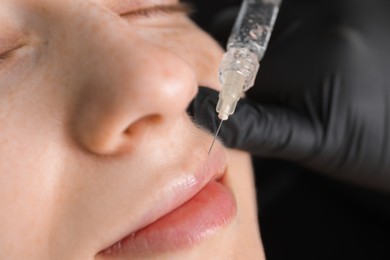 Photo of Cosmetologist giving lips injection to patient, closeup. Cosmetic surgery