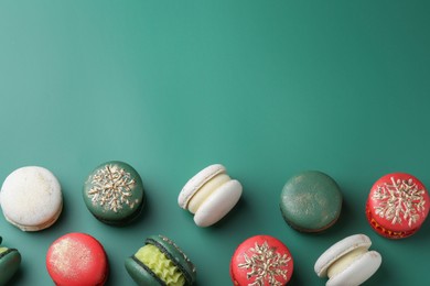 Beautifully decorated Christmas macarons on green background, flat lay. Space for text