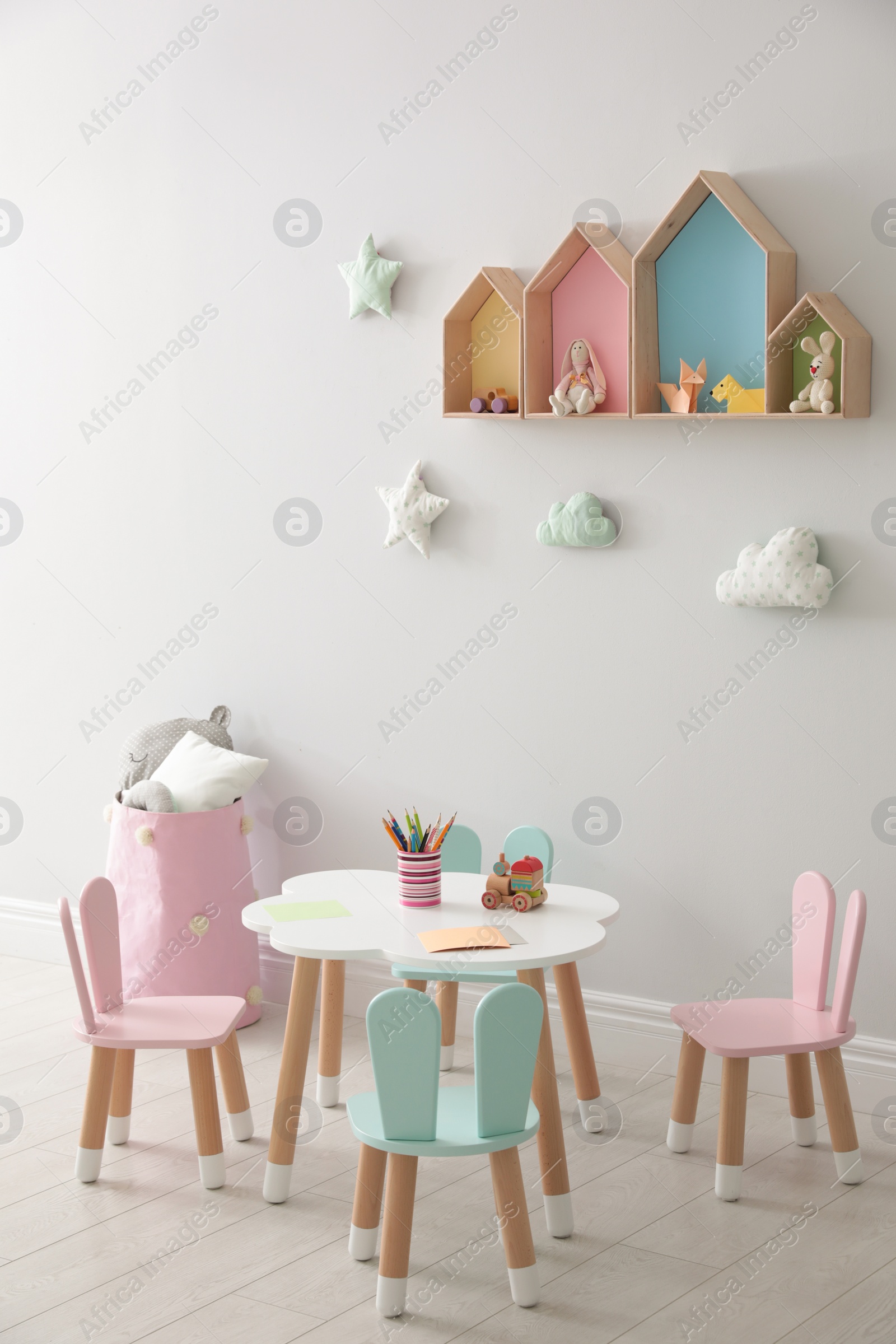 Photo of House shaped shelves and little table with chairs in children's room. Interior design