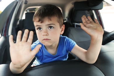Photo of Upset little boy closed inside car. Child in danger