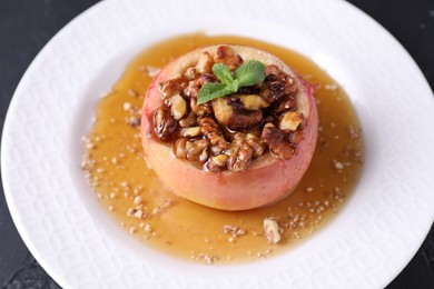 Tasty baked apple with nuts, honey and mint on table, closeup