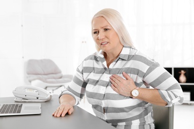 Mature woman having heart attack at workplace