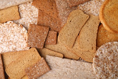 Photo of Fresh rye crispbreads, crunchy rice cakes and rusks as background, flat lay
