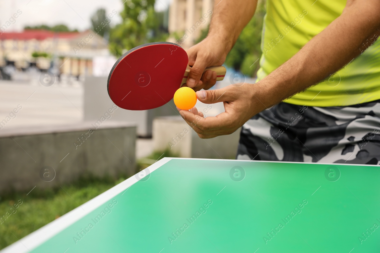 Photo of Man playing ping pong outdoors on summer day, closeup