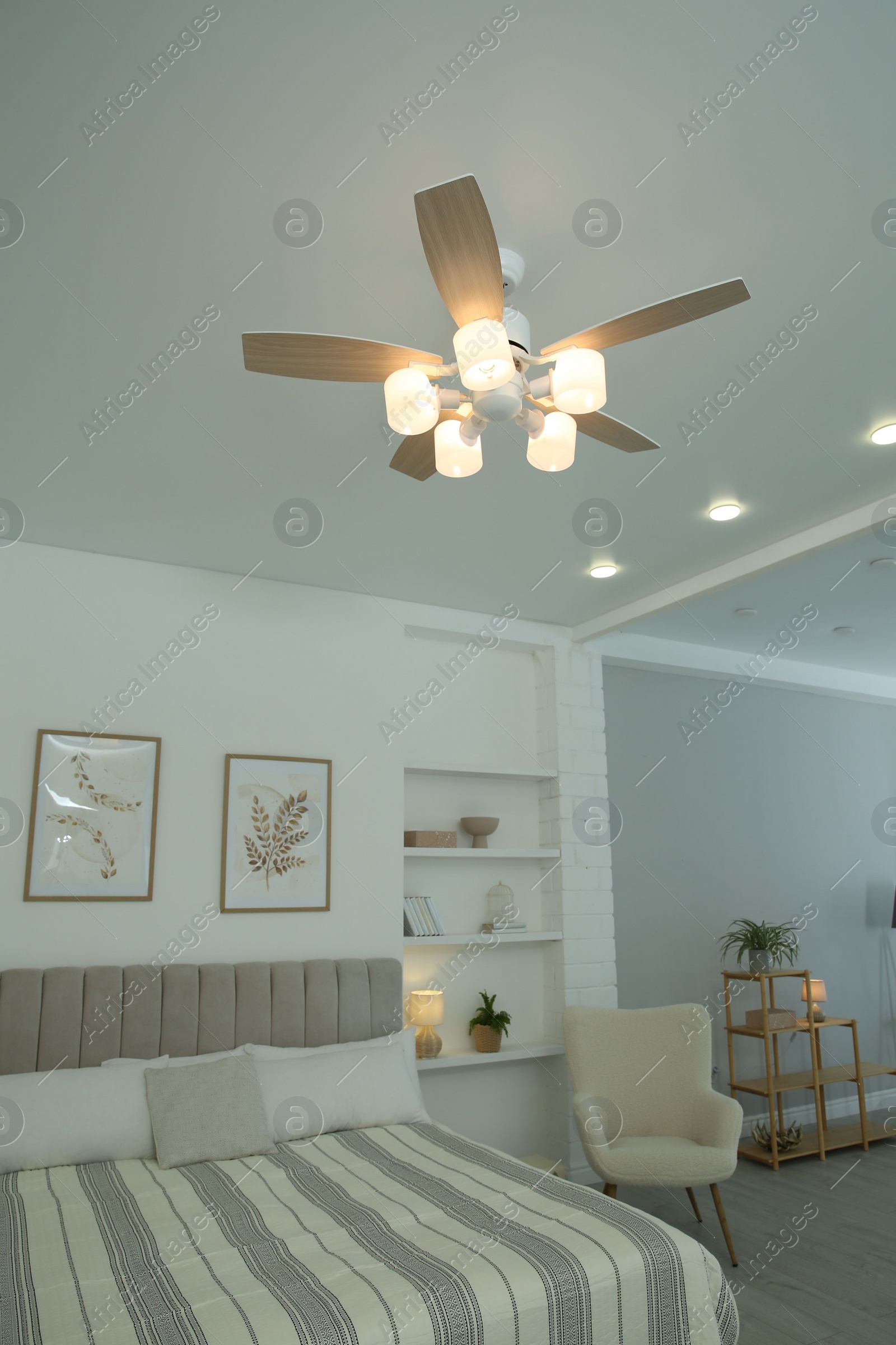 Photo of Ceiling fan, furniture and houseplants in stylish bedroom