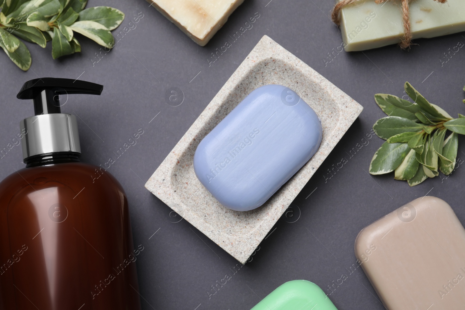 Photo of Soap bars and bottle dispenser on black background, flat lay