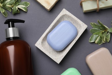 Soap bars and bottle dispenser on black background, flat lay