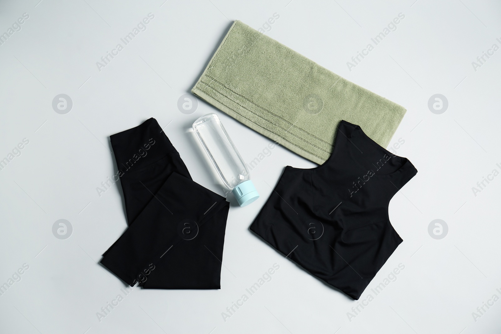 Photo of Sportswear, bottle of water and towel on grey background, flat lay. Yoga equipment