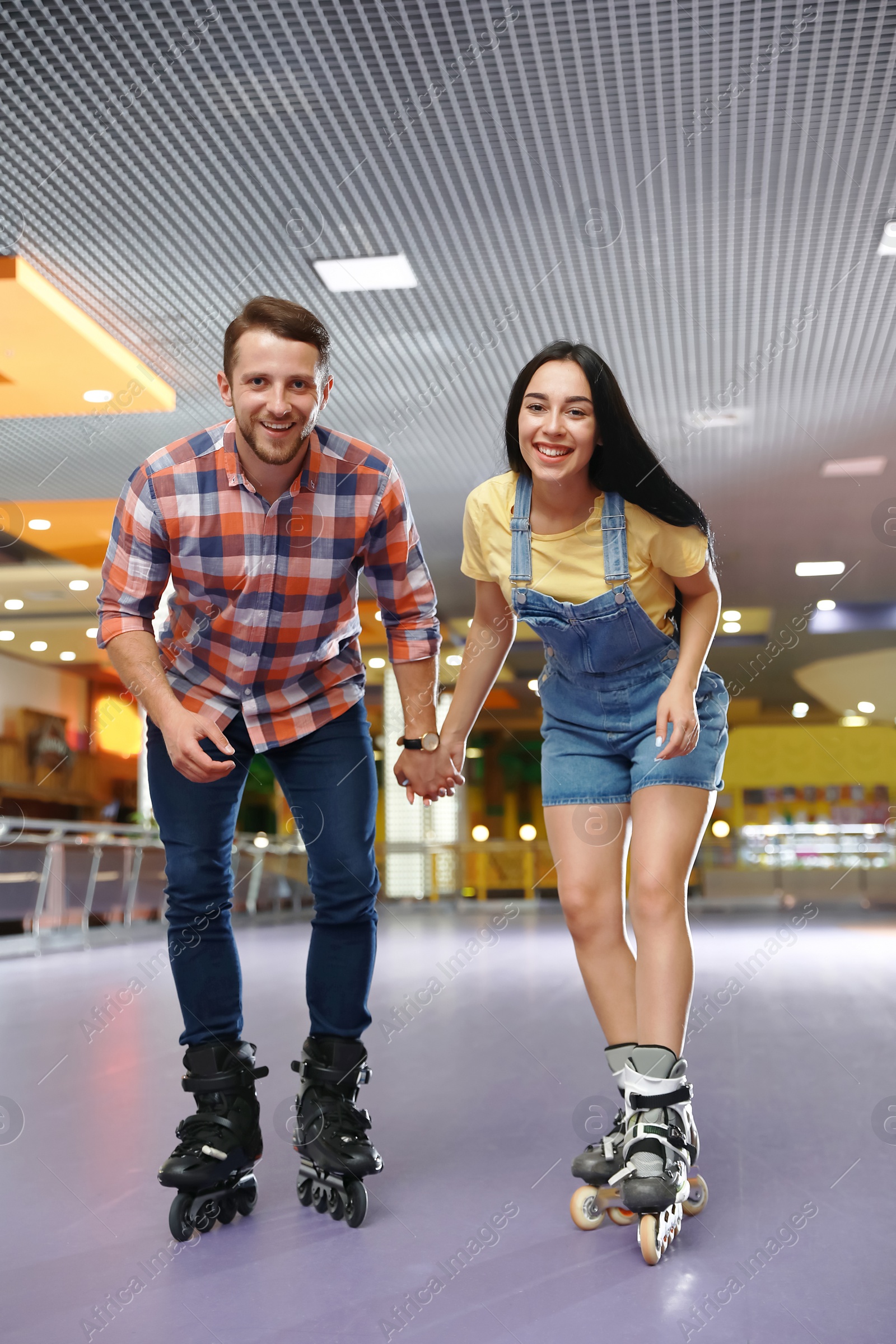 Photo of Young couple spending time at roller skating rink