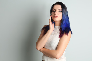 Photo of Young woman with bright dyed hair on light background, space for text