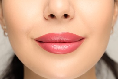 Woman with glossy lipstick on light background, closeup