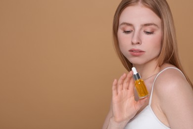 Beautiful young woman with essential oil on brown background. Space for text