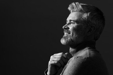 Photo of Portrait of smiling man on dark background, space for text. Black and white effect