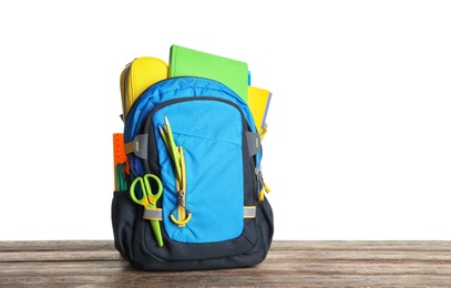 Photo of Backpack with school stationery on wooden table against white background