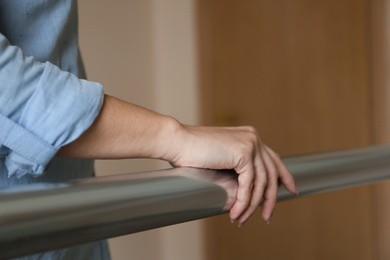 Photo of Woman leaning on metal railing indoors, closeup