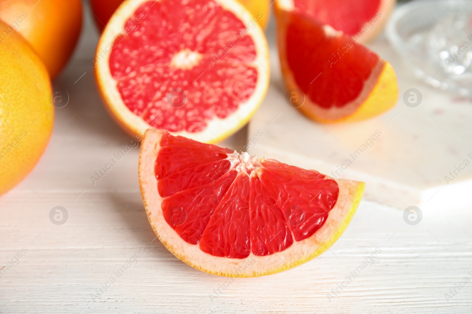 Photo of Cut and whole grapefruits on wooden table