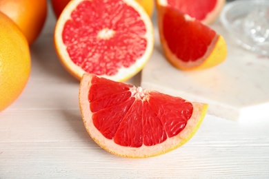 Photo of Cut and whole grapefruits on wooden table