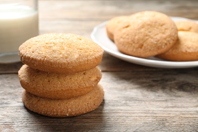 Photo of Tasty Danish butter cookies and milk on wooden table. Space for text