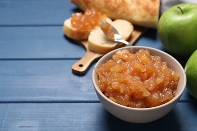 Photo of Bowl with delicious apple jam on blue wooden table, space for text