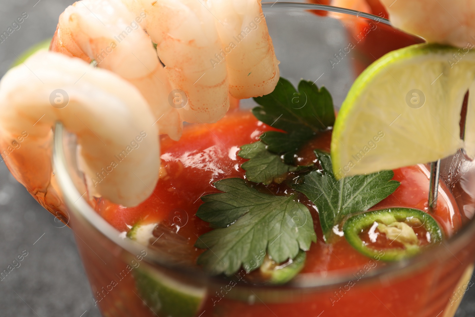 Photo of Tasty shrimp cocktail with sauce, lime and parsley in glass on table, closeup