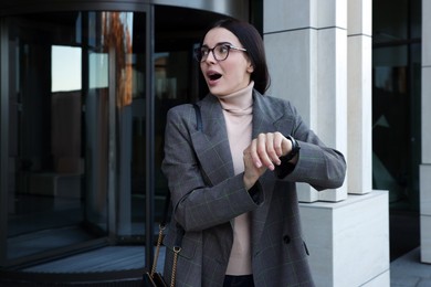 Emotional woman checking time on watch outdoors. Being late concept