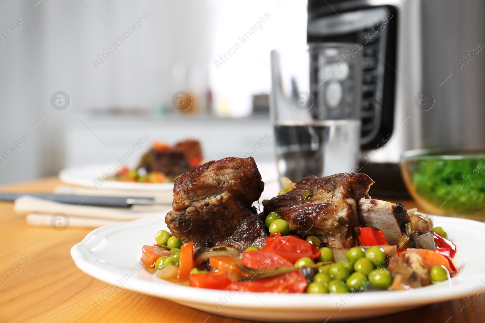 Photo of Plate with meat and garnish prepared in multi cooker on wooden table indoors, closeup. Space for text