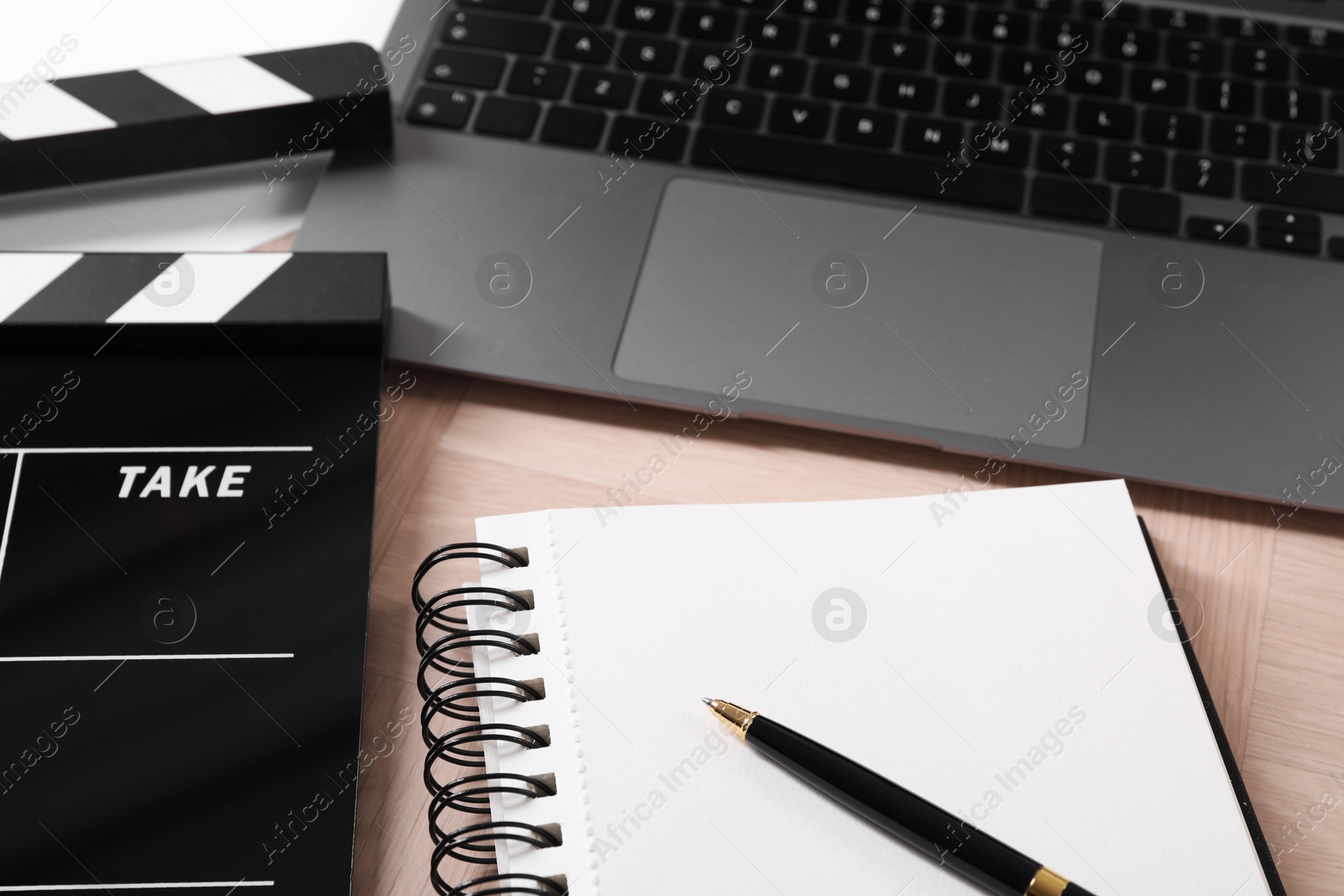 Photo of Movie clapper, notebook, pen and laptop on wooden table