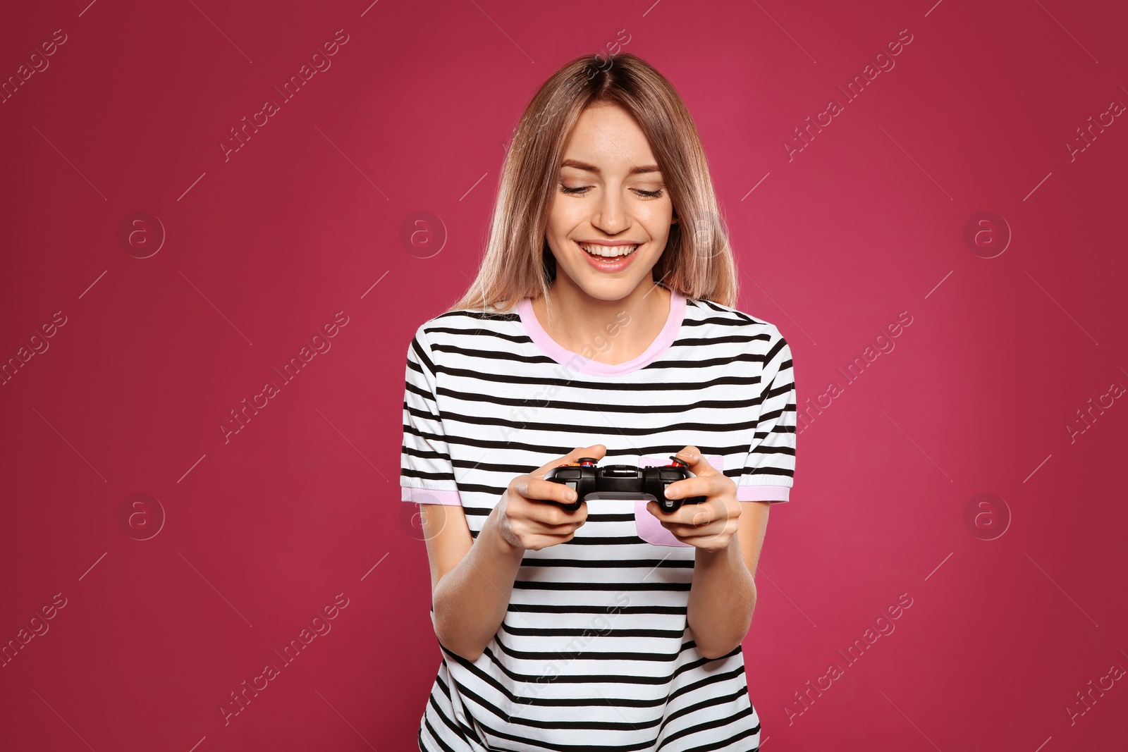 Photo of Emotional young woman playing video games with controller on color background