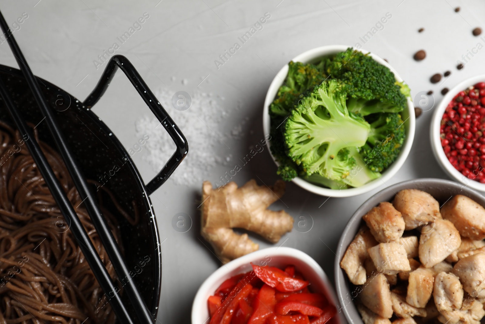 Photo of Wok with noodles, chicken and other products on light grey table, flat lay