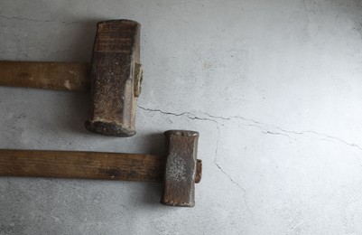 Two sledgehammers on grey textured background, top view. Space for text